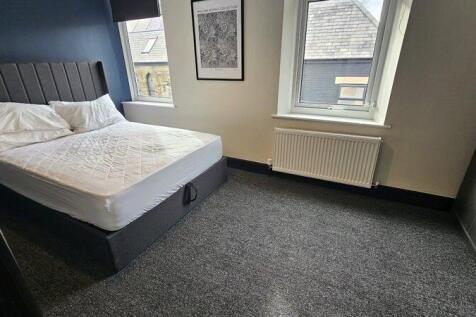 A neat and tidy bedroom featuring a large bed w...