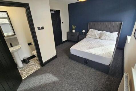 A clean and well-lit bedroom featuring a comfor...