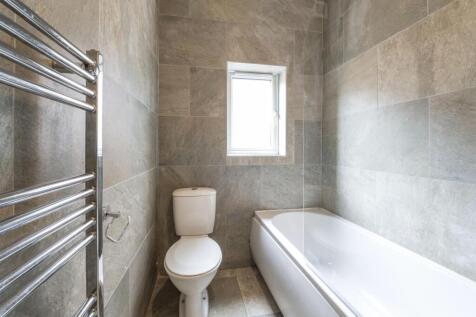 Bright, modern bathroom with tiled walls, a ful...