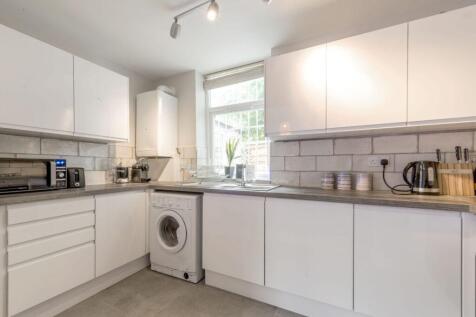 Bright modern kitchen with white cabinetry, int...