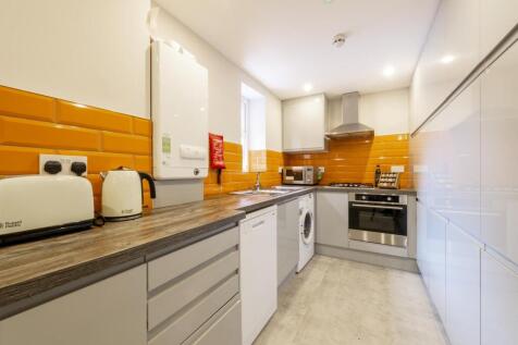 Modern galley kitchen with bright orange tiled ...