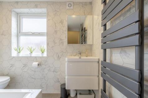 Bright, modern bathroom with patterned tiles, a...