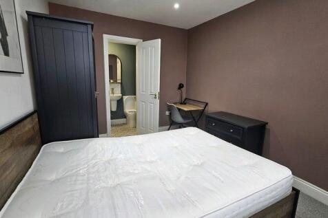 A cozy double bedroom featuring a sturdy wooden...