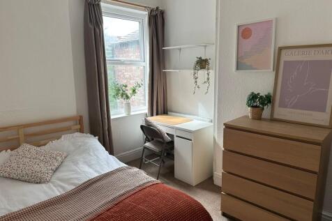 A cozy bedroom featuring a single bed with flor...