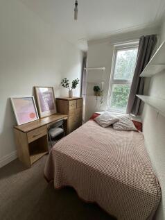 A cozy double bedroom with a large window allow...