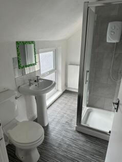 A bright, clean bathroom featuring a shower enc...