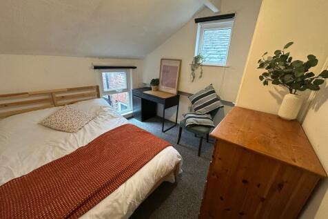 Cozy bedroom featuring a double bed with a wood...