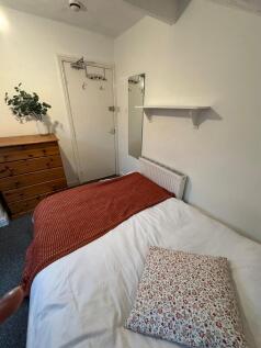 A modest bedroom with a neatly made bed featuri...