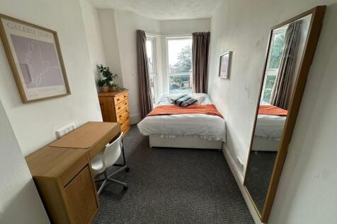 A well-lit, comfortable double bedroom with a c...