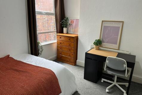 A cozy bedroom featuring a neatly made bed with...