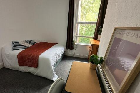 A cozy bedroom featuring a neatly made bed with...