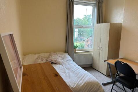 A cozy, well-lit room featuring a single bed wi...