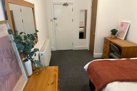 A cozy bedroom featuring a neatly made bed with...