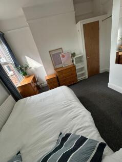 A cozy bedroom featuring a neatly made bed, nat...