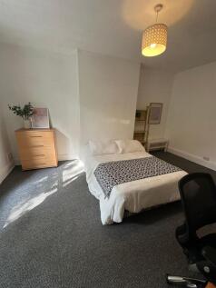 A well-lit, spacious master bedroom with a comf...