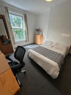 A bright and tidy bedroom featuring a comfortab...