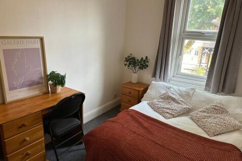 A cozy bedroom featuring a neatly made bed with...