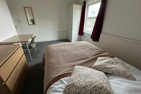 A cozy single bedroom featuring a comfortable b...