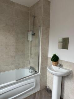 A clean and bright bathroom featuring a bathtub...