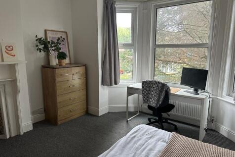 A well-lit bedroom featuring a large window wit...