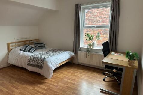 A tidy and bright bedroom featuring a comfortab...