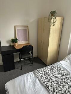 A cozy bedroom featuring a neatly made bed with...