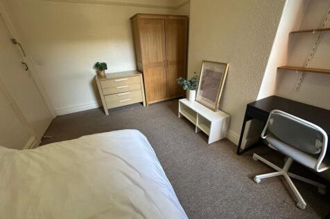 A cozy single bedroom featuring a neatly made b...