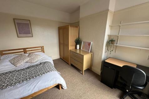 A cozy bedroom featuring a wooden bed frame wit...