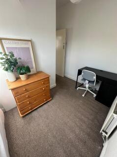 A cozy single bedroom featuring a wooden dresse...