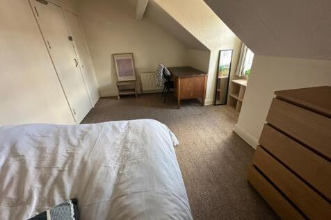 A cozy bedroom with a sloped ceiling, featuring...