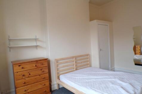 A cozy double bedroom featuring a wooden bed fr...