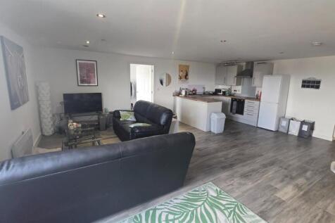 Spacious and well-lit living room featuring com...