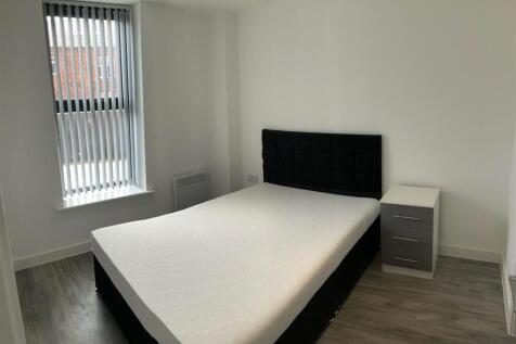 A clean and well-lit bedroom featuring a double...