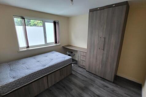 A cozy single bedroom with a window letting in ...