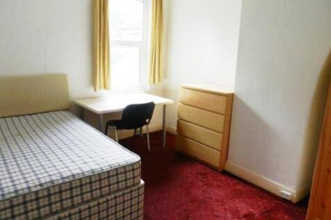 A modest single bedroom featuring a bed, window...