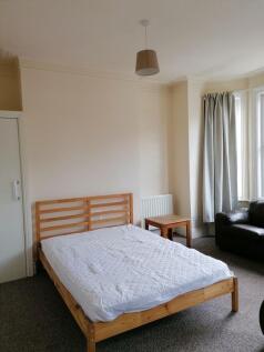 Bright double bedroom with a simple wooden bed ...