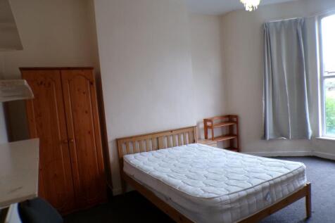 Bright double bedroom with a wooden bed frame a...