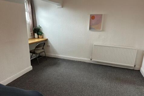 A bright, cozy bedroom with a small desk under ...