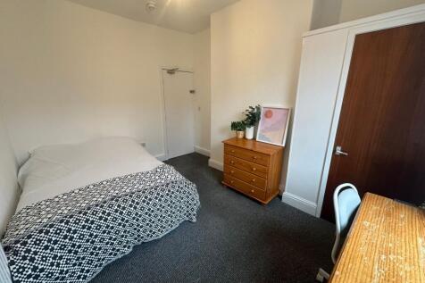 A cozy single bedroom featuring a neatly made b...