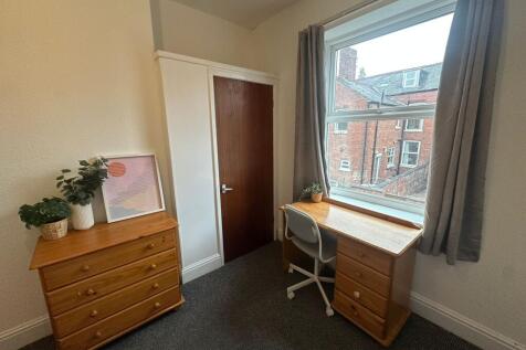 A bright and cozy bedroom featuring a large win...