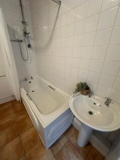 A compact, clean bathroom with a shower, small ...