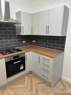Modern kitchen featuring sleek white cabinetry,...