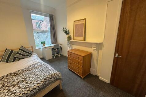 A cozy bedroom featuring a wooden bed frame wit...