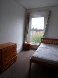 Bright bedroom with a large sash window and neu...