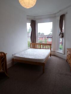 Bright double bedroom with a wooden bed frame p...