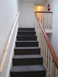 Carpeted interior staircase with wooden handrai...