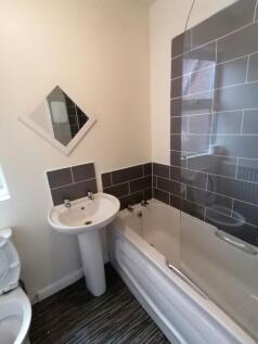 Clean, modern bathroom with a white bathtub and...