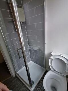 Modern tiled shower cubicle with glass door nex...
