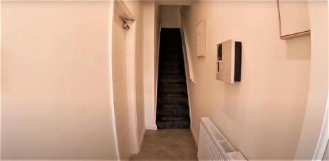 Bright narrow hallway with neutral walls, radia...