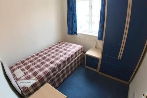 A cozy single bedroom featuring a small bed wit...